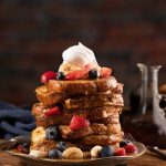 French,Toast,Stacked,High,And,Topped,With,Strawberries,,Blueberries,,Bananas,